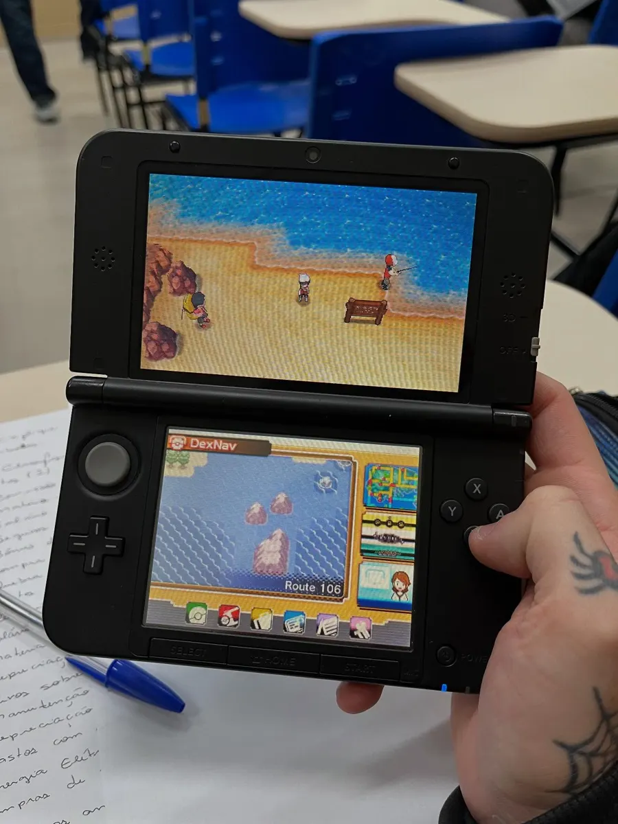 Mão tatuada segurando um videogame portátil